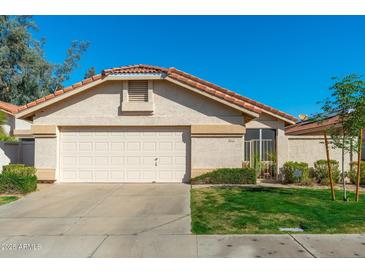 Charming single-Gathering home featuring a two-car garage and well-maintained front yard under a clear blue sky at 8812 E Riviera Dr, Scottsdale, AZ 85260