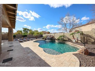 Large backyard with a luxurious pool, waterfall, basketball court, and covered patio at 14258 W Lisbon Ln, Surprise, AZ 85379