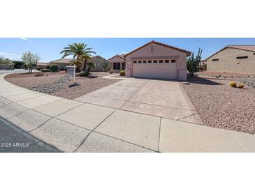 Single story home with low maintenance rock landscaping, mature palm trees, and a two car garage at 15561 W Vista Grande Ln, Surprise, AZ 85374