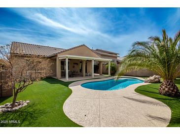 Beautiful backyard features an inviting pool, covered patio, and meticulously landscaped turf at 346 E Red Mesa Trl, San Tan Valley, AZ 85143