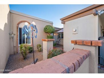 Charming courtyard features a decorative windmill, manicured shrubbery, and a glimpse of the home's inviting entrance at 1005 W Berridge Ln, Phoenix, AZ 85013