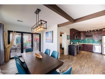 Bright dining room with modern lighting, a wood table with blue chairs, and a view of the outdoor patio at 2002 E Mitchell Dr, Phoenix, AZ 85016