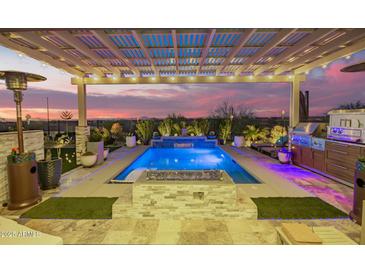 Inviting pool area featuring an outdoor kitchen, fire pit, pergola, and serene water feature for ultimate relaxation at 26716 W Ponderosa Ln, Buckeye, AZ 85396