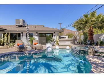 Inviting pool with spa, sun loungers, outdoor kitchen, and lush landscaping, perfect for relaxation and entertaining at 5137 E Flower St, Phoenix, AZ 85018