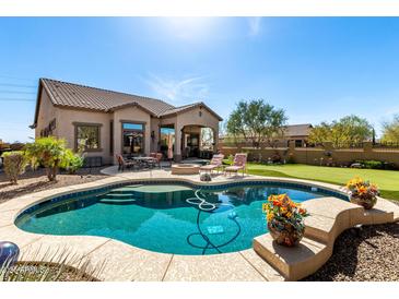 Backyard view with a beautiful sparkling blue pool, lush green grass and outdoor seating area at 8304 E Inca St, Mesa, AZ 85207