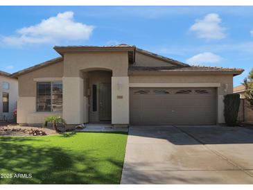 Tan single-story home with a two car garage, arched entry, and manicured lawn, offering curb appeal at 9477 W Tonopah Dr, Peoria, AZ 85382