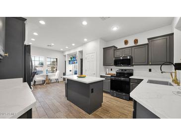 Modern kitchen with stainless steel appliances, gray cabinets, island, and breakfast nook with seating at 10942 E Sonrisa Ave, Mesa, AZ 85212