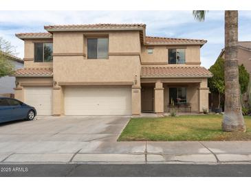 Two-story home boasts a three-car garage, desert landscaping, and a covered porch at 11868 W Kinderman Dr, Avondale, AZ 85323