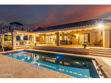 Stunning backyard oasis with a sparkling pool and inviting outdoor living space under string lights at twilight at 15646 E Sunflower Dr, Fountain Hills, AZ 85268