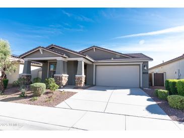 Charming single-story home featuring a neutral palette, stone accents, a well-manicured lawn, and a two-car garage at 19975 W Glenrosa Ave, Litchfield Park, AZ 85340