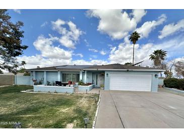 Charming single-story home with blue brick, green lawn, and a two car garage at 5146 W Echo Ln, Glendale, AZ 85302