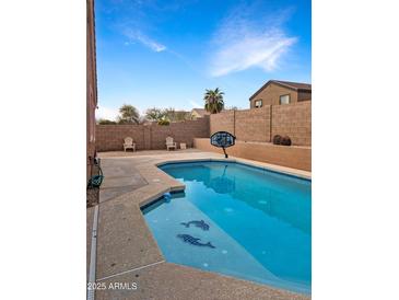 Enjoy the sparkling pool complete with dolphin tile, basketball hoop, and chairs for lounging at 528 E Wolf Hollow Dr, Casa Grande, AZ 85122