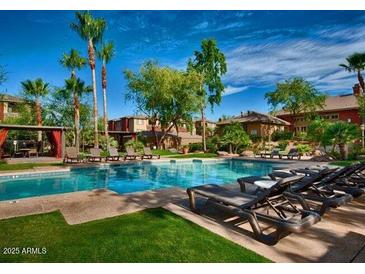 Relaxing community pool with lounge chairs and lush landscaping under a bright blue sky at 5401 E Van Buren St # 2053, Phoenix, AZ 85008