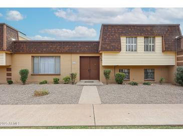 Charming two-story townhouse featuring neutral colors, double door entryway, and low-maintenance landscaping at 8442 E Chaparral Rd, Scottsdale, AZ 85250