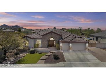 Charming home with a stone facade, arched entryway, three-car garage and desert landscaping at 9161 W Bajada Rd, Peoria, AZ 85383