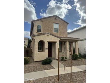 Two-story home features a welcoming front porch, desert landscaping, and neutral color palette at 10045 E Isleta Ave, Mesa, AZ 85209