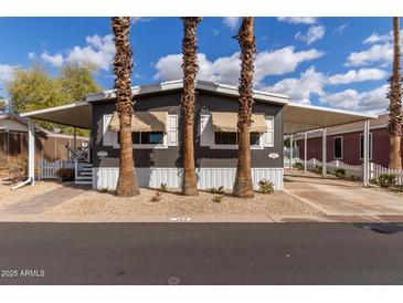 Charming mobile home with a covered carport and well-maintained landscaping, including palm trees at 201 S Greenfield Rd # 152, Mesa, AZ 85206