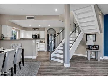 Open-concept kitchen with white cabinets, stainless steel appliances, and adjacent dining area with modern staircase at 10256 N 12Th Pl # 3, Phoenix, AZ 85020