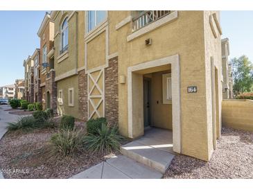 Charming townhome with textured stucco, brick accents, and desert landscaping providing curb appeal at 18250 N Cave Creek Rd # 164, Phoenix, AZ 85032