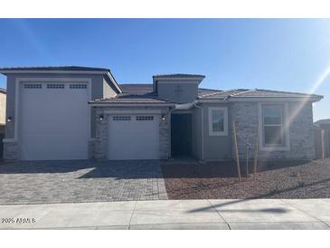 Charming single-story home featuring a three-car garage, stone accents, and a well-maintained front yard at 20285 W Monterey Way, Buckeye, AZ 85396