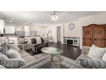 Spacious living room featuring hardwood floors, a stylish ceiling fan, and coordinated furnishings at 213 S 225Th Ln, Buckeye, AZ 85326