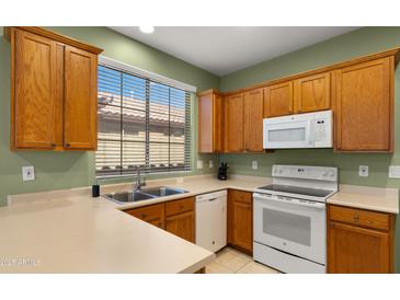 Bright kitchen features oak cabinets, a double basin sink beneath a window, and modern appliances at 3708 W Rushmore Dr, Anthem, AZ 85086