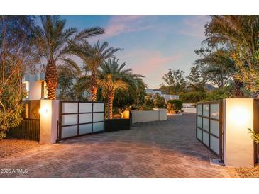 Elegant driveway with brick pavers and palm trees leading to a modern home at dusk at 6216 N 38Th Pl, Paradise Valley, AZ 85253