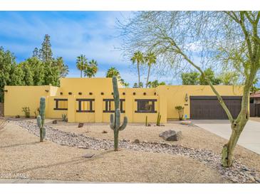 Charming yellow home with desert landscaping, cacti, and a quaint Southwest style at 7719 W Bluefield Ave, Glendale, AZ 85308