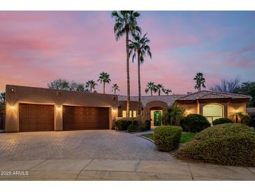 Beautiful home featuring a three-car garage, desert landscaping, and a secure gated entrance at 8924 E Charter Oak Dr, Scottsdale, AZ 85260