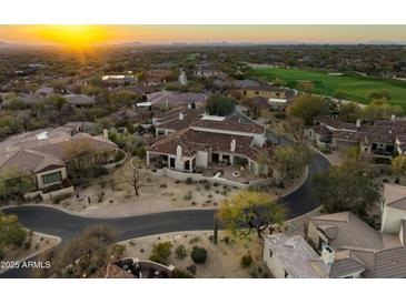 Stunning aerial view of a luxury home with a tile roof, lush landscaping, and a golf course nearby at sunset at 9280 E Thompson Peak Pkwy # 29, Scottsdale, AZ 85255