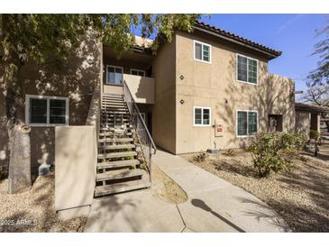 Inviting condo building with an exterior staircase, lush landscaping, and a well-maintained facade at 9450 E Becker Ln # 2090, Scottsdale, AZ 85260