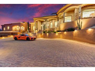 Mediterranean-style home at sunset featuring a paved circular driveway and a sports car at 14360 E Desert Cove Ave, Scottsdale, AZ 85259