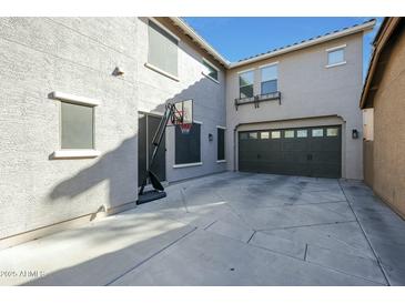 Spacious backyard with gray concrete, basketball hoop, and access to the garage at 18841 E Pelican Ct, Queen Creek, AZ 85142