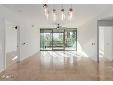 Bright, open living room with stone tile flooring and glass doors to a balcony view at 7120 E Kierland Blvd # 211, Scottsdale, AZ 85254