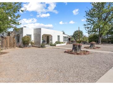 A charming, single-story home featuring a gravel front yard and a quaint covered porch entrance at 100 Swilling Ave, Wickenburg, AZ 85390