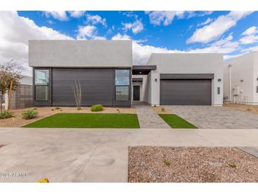 Modern home boasting a sleek design with gray tones, large windows, and well-manicured xeriscaped landscaping at 10302 E Utah Ave, Mesa, AZ 85212