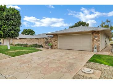 Charming single-story home with a two-car garage, manicured lawn, and patterned concrete driveway at 12534 W Ashwood Dr, Sun City West, AZ 85375