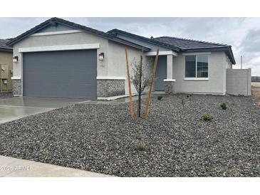 Charming single-story home featuring a two-car garage, well-kept lawn, and stone accents at 17162 W Corrine Dr, Surprise, AZ 85388