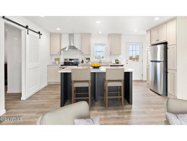 Modern kitchen featuring an island with seating, stainless steel appliances, and light wood flooring at 222 S Oak Rd, Maricopa, AZ 85139