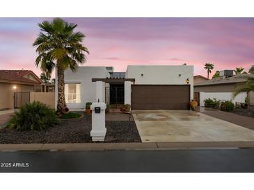 Charming single-story home with desert landscaping, palm tree and a two-car garage in a gated community at 10406 E Silvertree Dr, Sun Lakes, AZ 85248