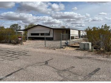 Charming single-story home featuring desert landscaping, fenced yard, and white siding under a cloudy sky at 10997 N Hualapai Dr, Casa Grande, AZ 85122