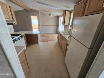 Functional kitchen featuring wood cabinets, a dual basin sink, and an adjacent dining area with ceiling fan at 10997 N Hualapai Dr, Casa Grande, AZ 85122