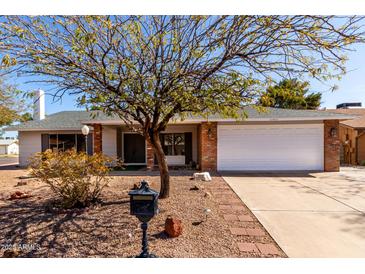 Charming single-story home featuring a two-car garage, brick accents, and a well-maintained desert landscaped front yard at 11451 S Half Moon Dr, Phoenix, AZ 85044