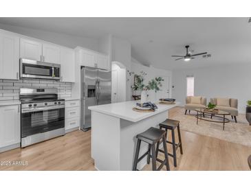 Bright kitchen boasts white cabinets, stainless steel appliances, subway tile backsplash, and an island with seating at 16611 N 19Th St, Phoenix, AZ 85022