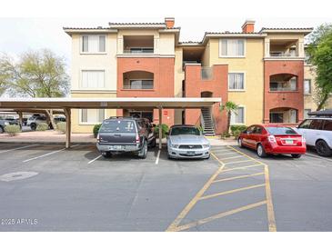 Apartment complex exterior with covered parking and several parked cars, landscaped with trees at 5401 E Van Buren St # 2095, Phoenix, AZ 85008