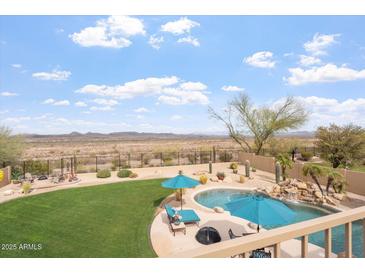 Inviting backyard featuring a sparkling pool, lush green lawn, desert landscaping, and mountain views at 9686 W Keyser Dr, Peoria, AZ 85383