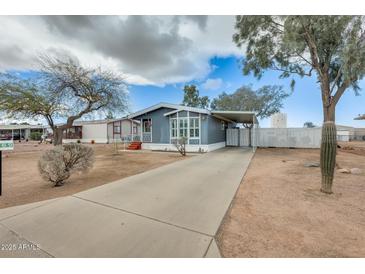 Charming blue home featuring a covered carport, well-maintained yard, and mature desert landscaping at 1669 N Suncrest Ave, Casa Grande, AZ 85122