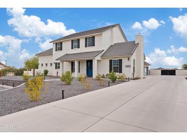 Charming two-story home with blue door, lush landscaping, and wide driveway at 2457 W Phillips Rd, Queen Creek, AZ 85144