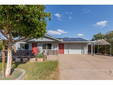 Charming single-story home featuring a red door, solar panels, and a covered parking area at 3027 S Clementine Dr, Tempe, AZ 85282