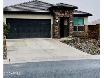 Charming single-story home featuring a stone entrance, dark garage door, and low-maintenance desert landscaping at 8836 S 165Th Ave, Goodyear, AZ 85338